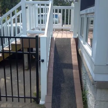 Accessible deck walkway with white railings and a black gate