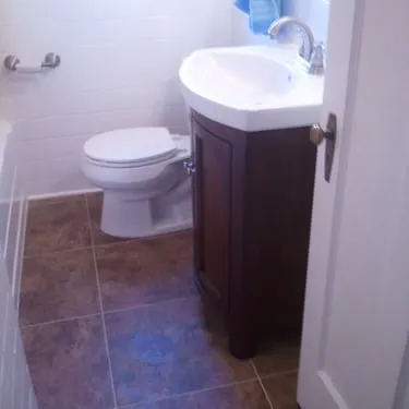Bathroom flooring beside a dark wood vanity and toilet