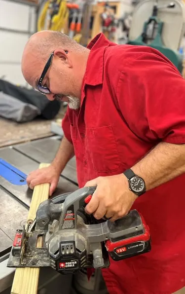 Kirk Metz using a cordless planer on a piece of wood in a workshop